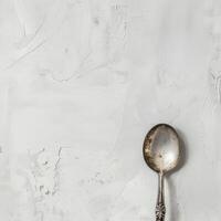 ai generato minimalista stile argento cucchiaio su bianca sfondo superiore Visualizza foto