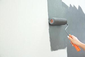 rullo spazzola la pittura, lavoratore pittura su superficie parete pittura appartamento, Restaurare con grigio colore dipingere. partire vuoto copia spazio bianca per Scrivi descrittivo testo accanto. foto