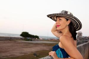 bellissimo donna indossare il tradizionale colombiano cappello chiamato sombrero vueltiao a il storico muri di cartagena de indie foto