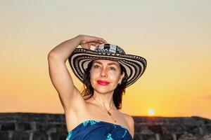 bellissimo donna indossare il tradizionale colombiano cappello chiamato sombrero vueltiao a il storico muri di cartagena de indie foto