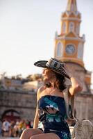 bellissimo donna indossare il tradizionale colombiano cappello chiamato sombrero vueltiao a il orologio Torre su il storico strade di il cartagena de indie murato città foto