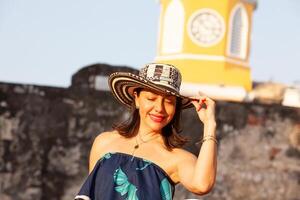 bellissimo donna indossare il tradizionale colombiano cappello chiamato sombrero vueltiao a il orologio Torre su il storico strade di il cartagena de indie murato città foto