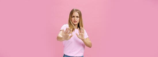 restare lontano a partire dal me. intenso preoccupato e scontento donna essere vittima di sessuale molestia raccolta palme nel difensiva gesto fabbricazione passo indietro accigliato chiede fermare, rifiuto al di sopra di rosa parete foto