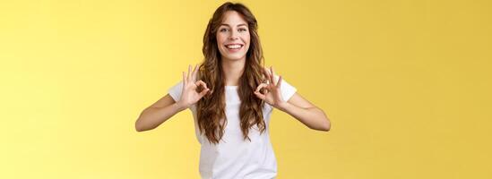 affare io garanzia eccellente risultati. bella vista amichevole piacevole giovane donna assicurare qualunque cosa va bene mostrare ok Perfetto gesto sorridente fiducioso rilassato In piedi giallo sfondo promettere essere bene foto