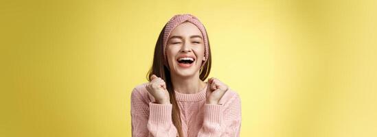 sollevato contento trionfante attraente europeo donna indossare rosa a maglia maglione urla sì soddisfatto, raccolta pugni nel vittoria vicino occhi sorridente, festeggiare vincita, sensazione fortunato udito bene notizia foto