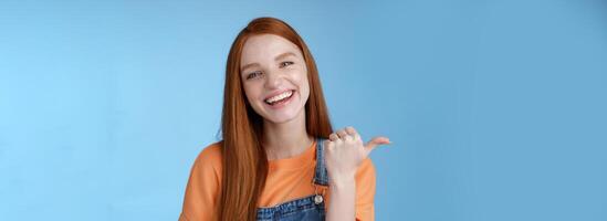 ragazza introducendo sua amico puntamento pollice sinistra sorridente ridendo con gioia con orgoglio telling professionisti freddo Prodotto raccomandare telling di accogliente bar gustoso caffè avendo divertimento in posa blu sfondo foto