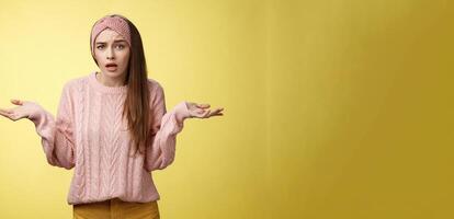 che cosa grande affare, perché così chiasso. frustrato confuso e all'oscuro carino giovane bella donna nel a maglia maglione, fascia per capelli alzando le spalle nel sgomento chiede domanda ignaro che cosa accadendo foto