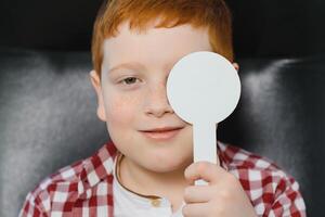 bambino a occhio vista test. poco ragazzo Selezione bicchieri a ottico negozio. vista misurazione per scuola bambini. occhio indossare per bambini. medico l'esecuzione occhio dai un'occhiata. ragazzo con spettacoli a lettera grafico foto