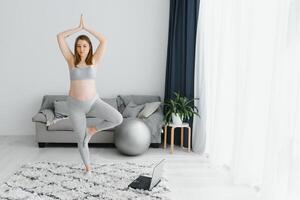 salutare gravidanza yoga e fitness concetto. giovane incinta yoga donna Lavorando su nel vivente camera interno. foto