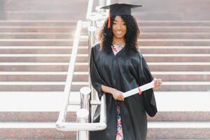 studente laureato afroamericano allegro con il diploma in sua mano foto