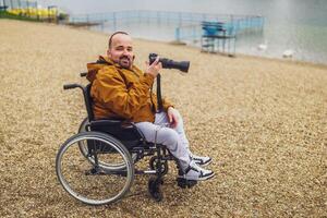 paraplegico portatori di handicap uomo nel sedia a rotelle è Fotografare all'aperto. foto