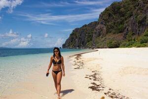 donna a piedi su il bene sabbia di un' tropicale spiaggia su un' soleggiato giorno. foto