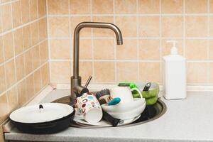 un' mucchio di sporco piatti, tazze, piatti nel il lavello. foto