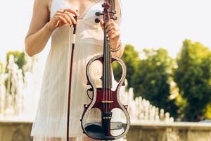 un' frammento di un elettrico violino, un' violino nel il mani di un' del musicista ragazza foto