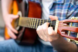 mani di un' giovane uomo giocando il chitarra. avvicinamento. selettivo messa a fuoco. foto