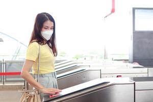 concetto di traffico e trasporto. asiatico femmina viaggiatori indossare maschere automatico lettura per il skytrain stazione nel il città. vita nel il capitale città foto