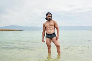 giovane muscolare uomo esercizio su il spiaggia, giovane muscolare uomo fare bodybuilding esercizi su il spiaggia, atletico giovane uomo su il spiaggia foto