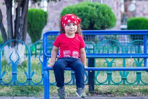 contento poco ragazzo giocando nel il parco, lungo capelli ragazzo nel il parco foto