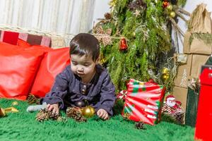 il poco bambino giocando con Natale decorazioni nel studio, poco bambino con Natale palla foto