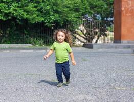 contento poco ragazzo giocando nel il parco, lungo capelli ragazzo nel il parco foto