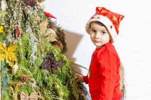 il poco bambino giocando con Natale decorazioni nel studio, poco bambino con Natale palla foto