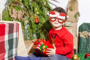 il poco bambino giocando con Natale decorazioni nel studio, poco bambino con Natale palla foto