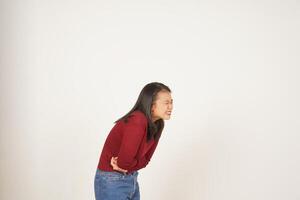 giovane asiatico donna nel rosso maglietta sofferenza mal di stomaco, dolore su stomaco isolato su bianca sfondo foto