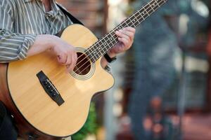 uomo giocando acustico basso chitarra a all'aperto evento, vicino su Visualizza per chitarra collo foto