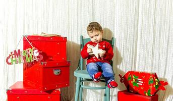 il poco bambino giocando con Natale decorazioni nel studio, poco bambino con Natale palla foto