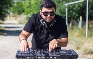 dj con cuffie e miscelatore nel il parco, il dj a opera foto