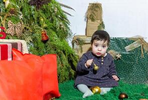 il poco bambino giocando con Natale decorazioni nel studio, poco bambino con Natale palla foto