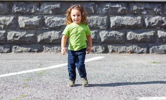 contento poco ragazzo giocando nel il parco, lungo capelli ragazzo nel il parco foto