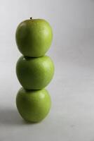 un' pila di tre verde mele su bianca sfondo foto