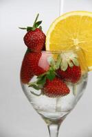 un' bicchiere di acqua con fragole e un arancia fetta foto