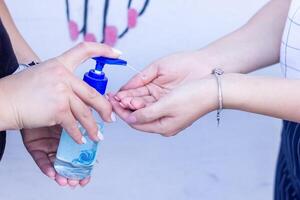 Due ragazze lavaggio loro mani con alcogel foto