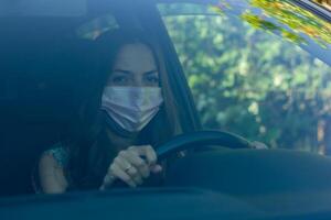 giovane donna nel macchina, giovane donna con protettivo maschera guida auto foto