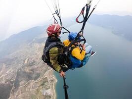 parapendio nel il montagne, il Due persone su il superiore di il montagna, il paracadutisti siamo volante con un' paracadute foto