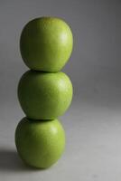 un' pila di tre verde mele su bianca sfondo foto