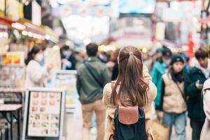 turista donna visitare ameyoko mercato, un' occupato mercato strada collocato nel ueno. punto di riferimento e popolare per turista attrazione e viaggio destinazione nel tokyo, Giappone e Asia concetto foto