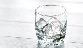 bicchiere con ghiaccio cubi su il di legno tavolo foto