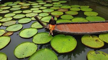 fuco tiro di ragazza su barca circondato di Vittoria amazonica naturale paesaggio acquatico impianti foto