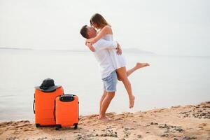 giovane coppia con valigia su il spiaggia nel estate giorno. il concetto di ricreazione a mare e viaggio foto