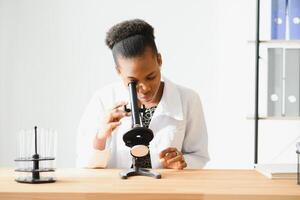 africano americano femmina laboratorio tecnico guardare attraverso microscopio nel laboratorio. foto