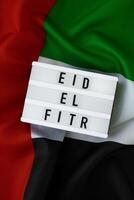 eid EL Fitr - eid mubarak - contento vacanze testo telaio su unito arabo Emirates agitando bandiera fatto a partire dal seta Materiale. pubblico vacanza celebrazione sfondo. il nazionale bandiera di emirati arabi uniti. patriottismo commemorazione giorno musulmano Ramadan benedetto santo mese concetto foto