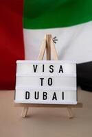 lightbox con testo Visa per dubai su sfondo di agitando Emirati Arabi Uniti bandiera fatto a partire dal seta. unito arabo Emirates bandiera con concetto di turismo e in viaggio. invitante saluto carta, annuncio. dubai accogliente carta foto