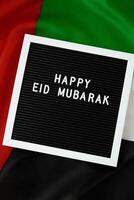 Congratulazioni con testo contento eid mubarak - contento vacanze agitando Emirati Arabi Uniti bandiera su sfondo concetto. saluto carta annuncio. commemorazione giorno musulmano Ramadan benedetto santo mese pubblico vacanza. patriottismo foto