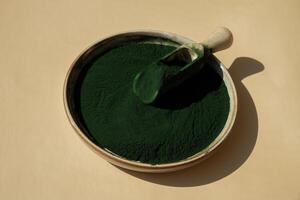 naturale biologico verde spirulina alghe polvere nel ciotola e di legno cucchiaio su neutro sfondo. clorella alga marina vegano superfood supplemento fonte e disintossicazione. copia spazio salutare nutritivo antiossidante concetto foto