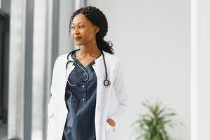 ritratto di femmina africano americano medico in piedi nel sua ufficio a clinica. foto