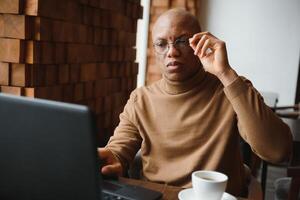 africano americano attività commerciale uomo con il computer portatile nel un' bar. foto