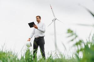 vento turbine generando elettricità. energia conservazione concetto e lavoratore personale ingegnere hold tavoletta foto